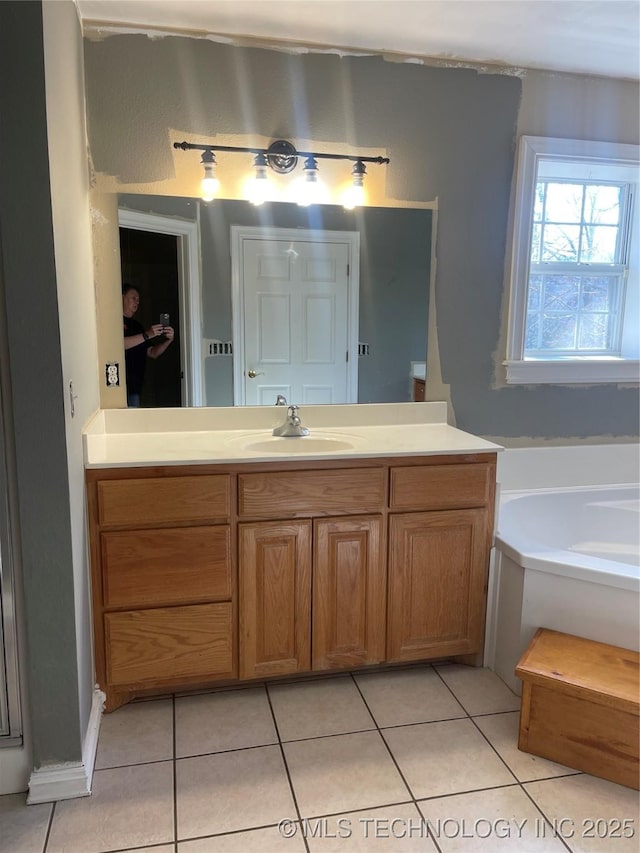 full bath with vanity, a garden tub, and tile patterned flooring