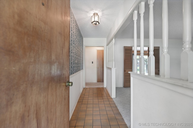 corridor featuring carpet, tile patterned flooring, and a textured ceiling