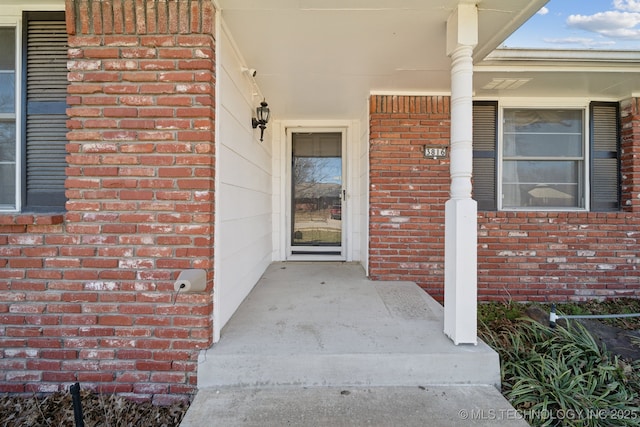 view of exterior entry with covered porch and brick siding