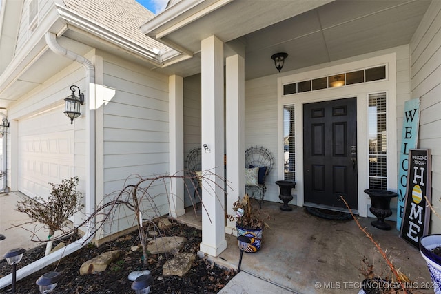 entrance to property featuring an attached garage and roof with shingles