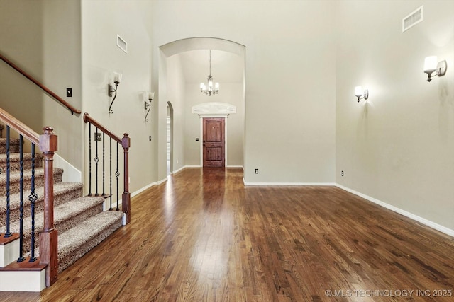 foyer with arched walkways, visible vents, stairs, and wood finished floors