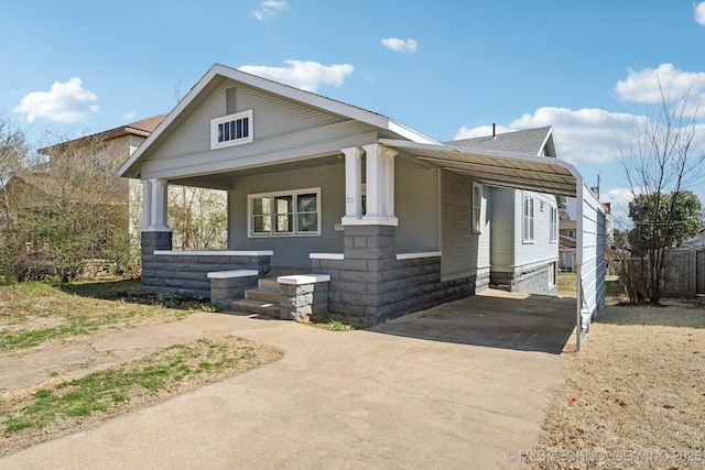 view of front of property featuring a carport, brick siding, covered porch, and driveway