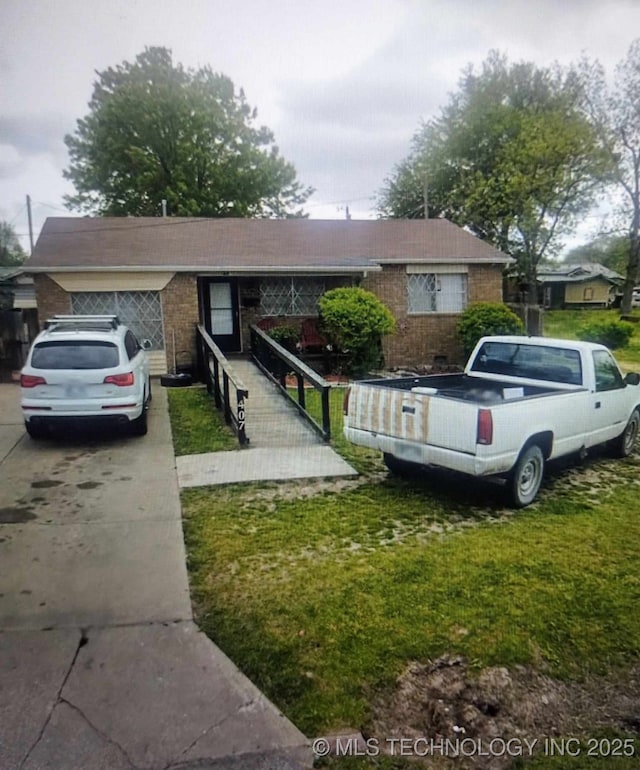 view of front of home with a front yard, brick siding, and driveway