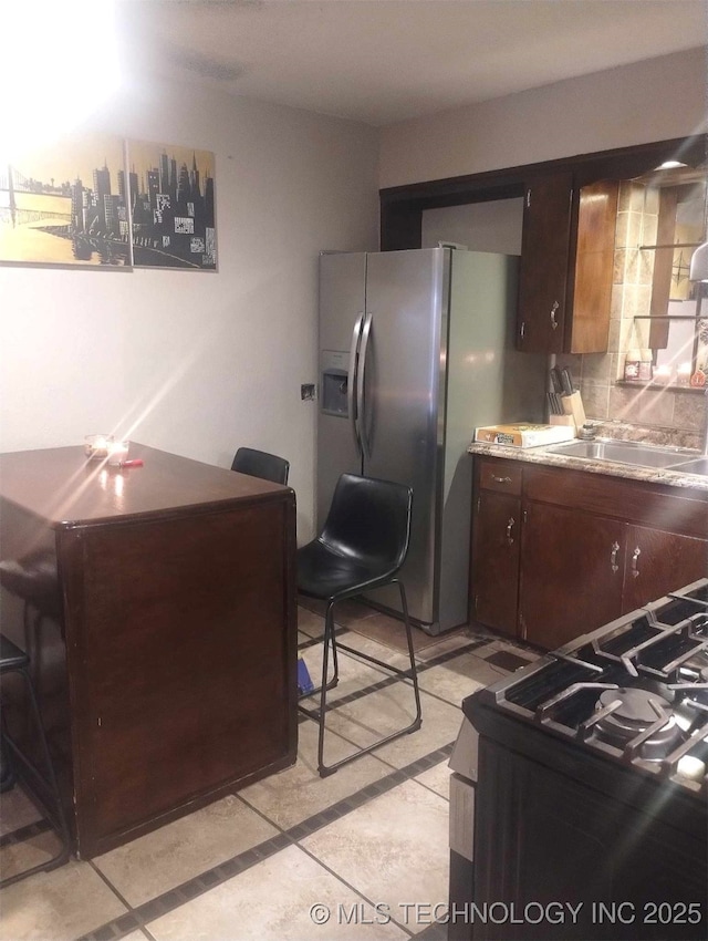 kitchen with dark brown cabinets, appliances with stainless steel finishes, light countertops, and a sink