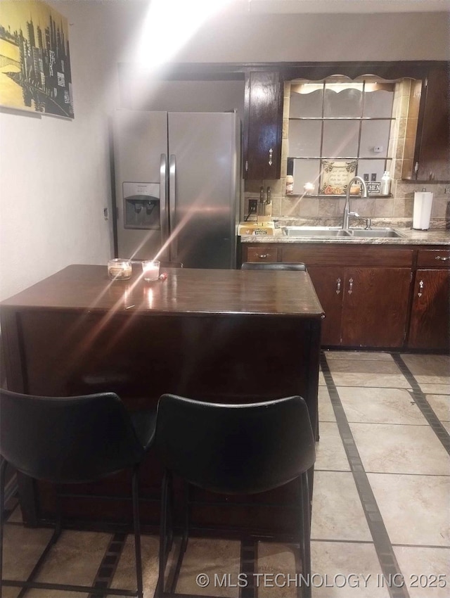 kitchen featuring a sink, backsplash, and stainless steel fridge with ice dispenser