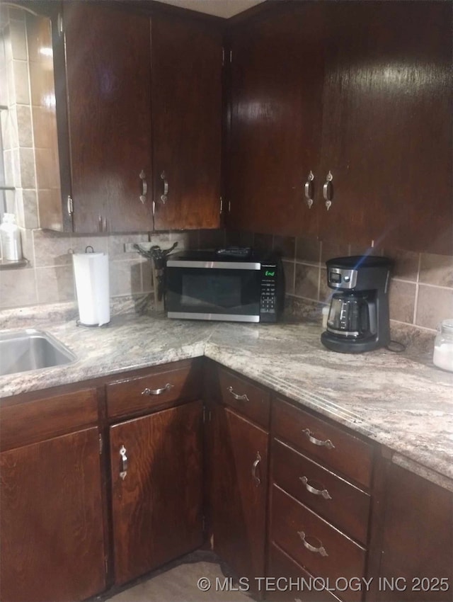 kitchen featuring stainless steel microwave, dark brown cabinets, and decorative backsplash