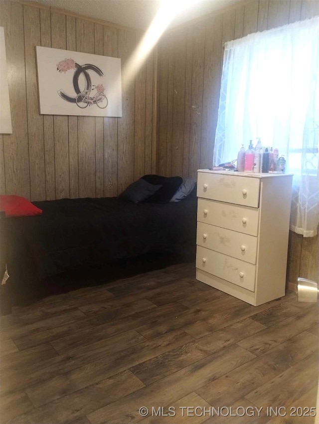 bedroom with multiple windows, dark wood-type flooring, and wood walls