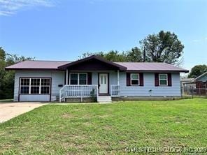 view of front facade with covered porch, driveway, and a front lawn