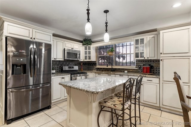 kitchen with light tile patterned flooring, appliances with stainless steel finishes, tasteful backsplash, and glass insert cabinets