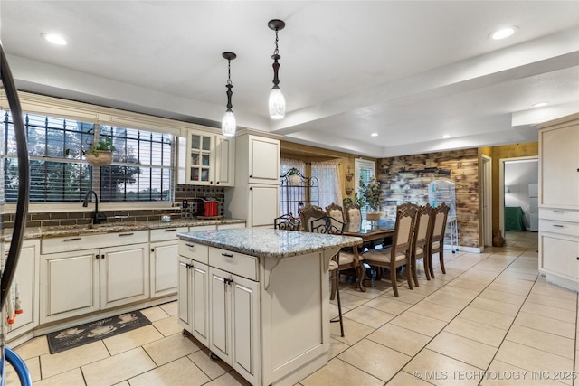 kitchen featuring decorative light fixtures, decorative backsplash, light tile patterned flooring, and a sink