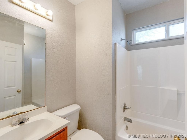 bathroom with vanity, toilet, a textured wall, and tub / shower combination