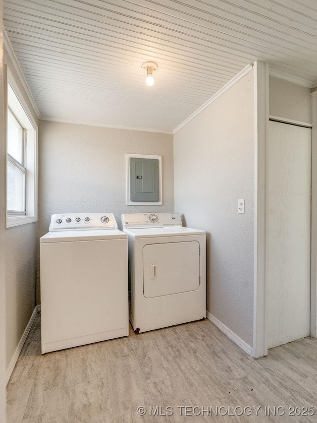 clothes washing area featuring laundry area, electric panel, ornamental molding, washer and dryer, and light wood-type flooring