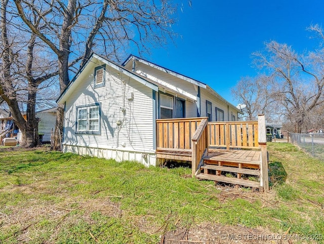 back of property featuring a yard, a deck, and fence