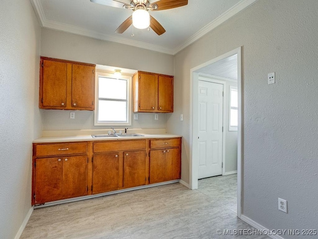 kitchen with crown molding, light countertops, brown cabinets, and a sink