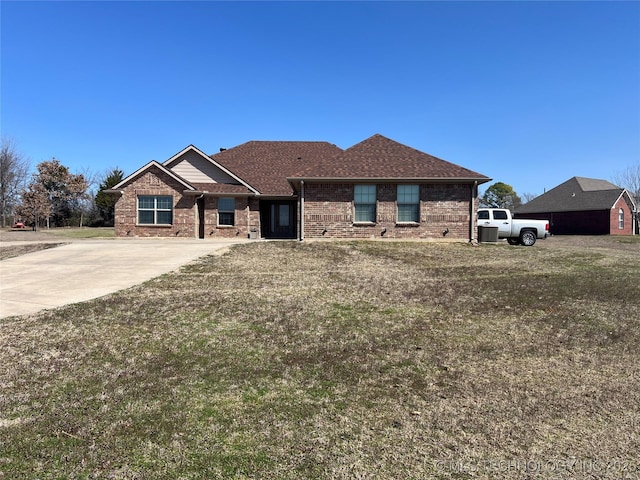 view of front facade with brick siding, concrete driveway, a shingled roof, and a front lawn