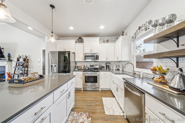 kitchen with open shelves, stainless steel appliances, dark countertops, and white cabinetry