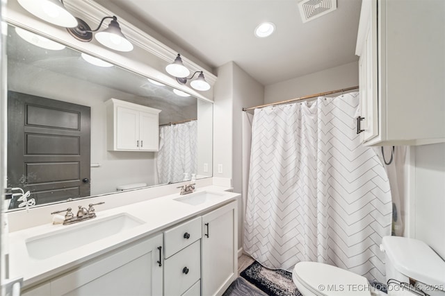 bathroom with double vanity, toilet, visible vents, and a sink