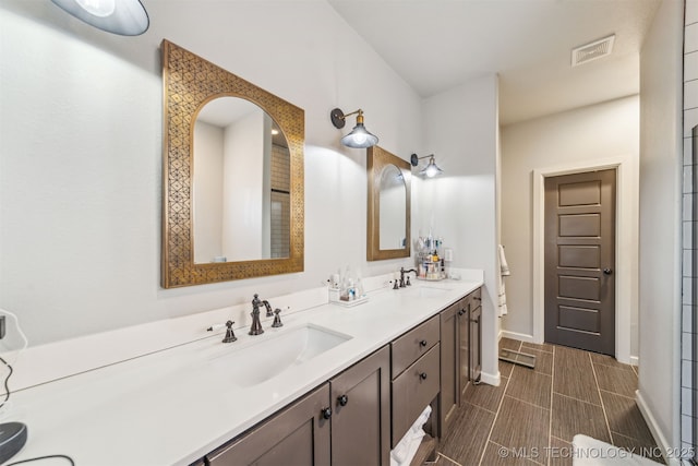 bathroom featuring double vanity, baseboards, visible vents, and a sink