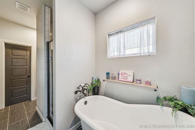 full bath featuring a freestanding tub, visible vents, and a shower stall