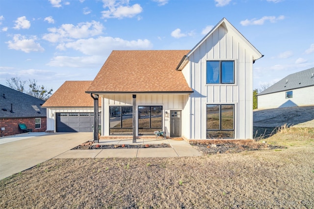 modern farmhouse featuring a garage, board and batten siding, driveway, and a shingled roof