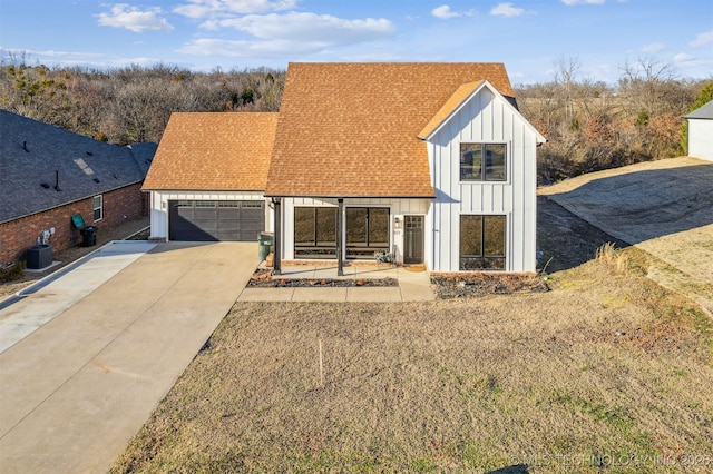 modern farmhouse style home featuring driveway, central AC, roof with shingles, board and batten siding, and a garage