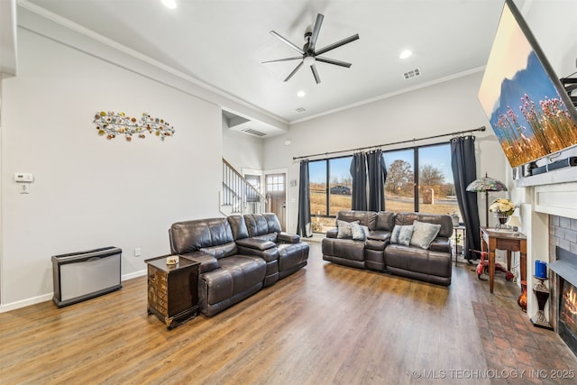 living area with wood finished floors, visible vents, baseboards, a fireplace, and ornamental molding