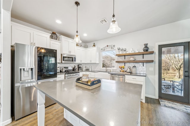 kitchen featuring tasteful backsplash, visible vents, appliances with stainless steel finishes, light wood-style floors, and white cabinetry