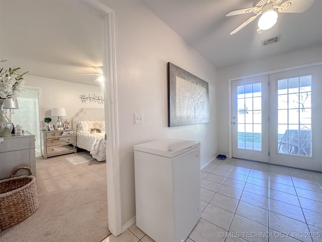 interior space with visible vents, baseboards, ceiling fan, light tile patterned floors, and light carpet