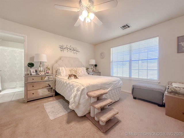 carpeted bedroom featuring visible vents, connected bathroom, baseboards, and ceiling fan