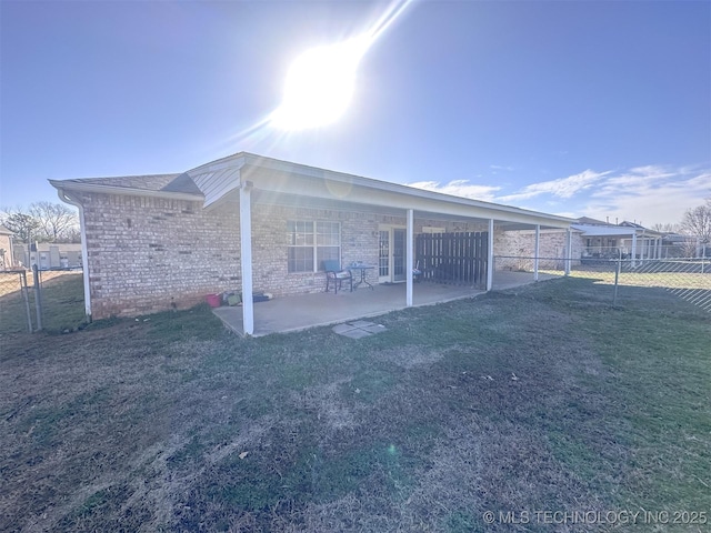 rear view of house featuring a yard, a patio area, brick siding, and fence