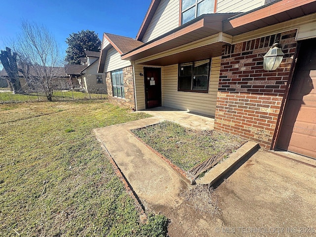 property entrance featuring a yard, brick siding, and fence