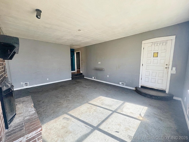 unfurnished living room with visible vents, baseboards, and a brick fireplace