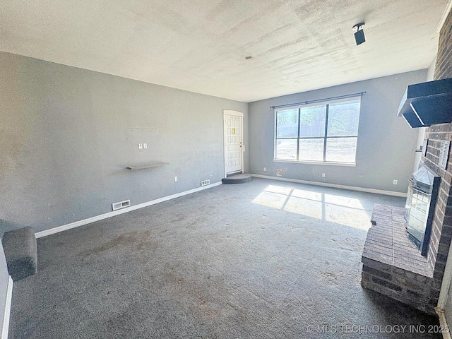 unfurnished living room featuring a brick fireplace, baseboards, visible vents, and carpet floors