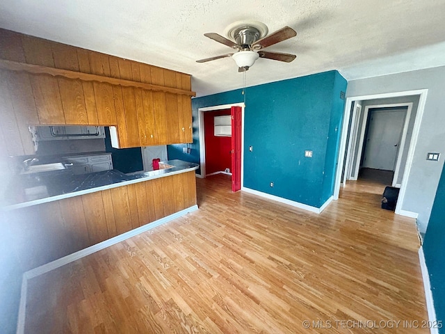 kitchen featuring brown cabinets, a textured ceiling, light wood-style floors, and ceiling fan