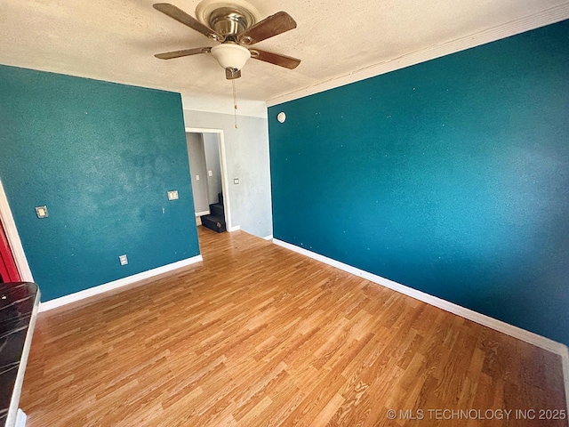 unfurnished room featuring ceiling fan, wood finished floors, baseboards, and a textured ceiling