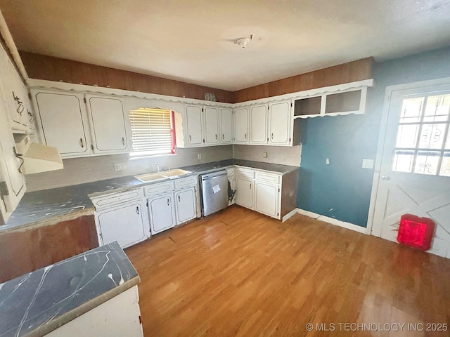 kitchen with a sink, stainless steel dishwasher, a wealth of natural light, and light wood finished floors