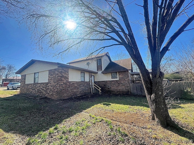 view of home's exterior featuring brick siding, a yard, and fence