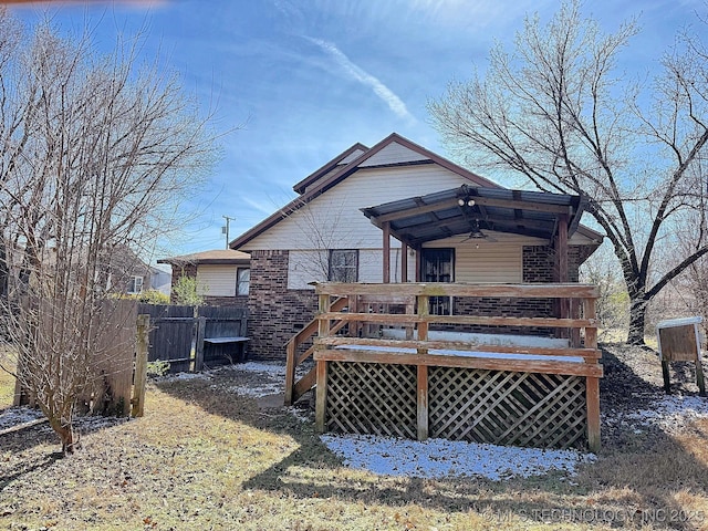 rear view of house featuring a deck, fence, brick siding, and ceiling fan