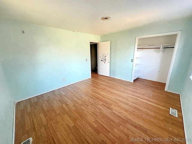 unfurnished bedroom with light wood-style floors, visible vents, and a closet