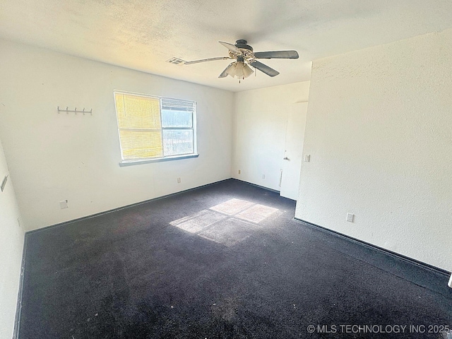 carpeted spare room with visible vents, a textured ceiling, and ceiling fan