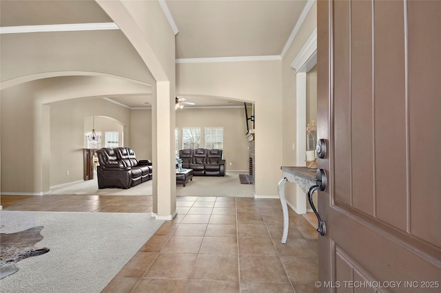 entrance foyer featuring arched walkways, light tile patterned floors, light carpet, and ornamental molding