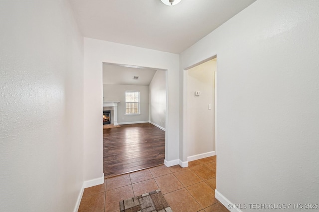 corridor featuring baseboards and tile patterned flooring