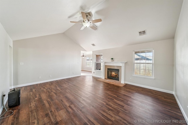 unfurnished living room featuring a wealth of natural light, a fireplace with flush hearth, ceiling fan, and wood finished floors