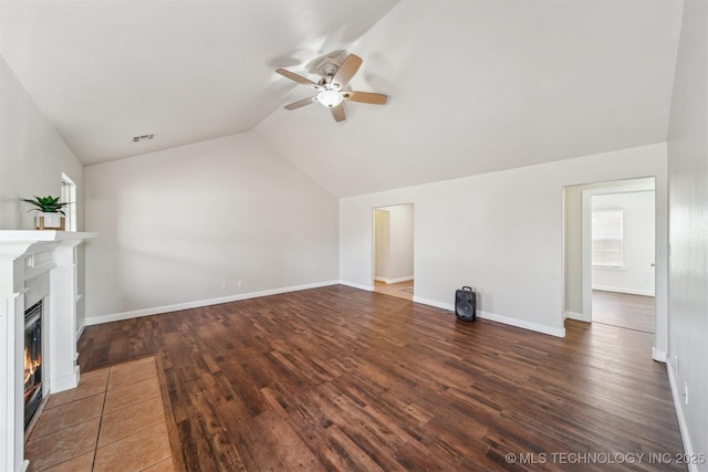 unfurnished living room featuring a glass covered fireplace, vaulted ceiling, wood finished floors, and baseboards