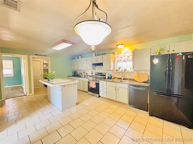 kitchen with visible vents, a kitchen island, under cabinet range hood, appliances with stainless steel finishes, and a sink