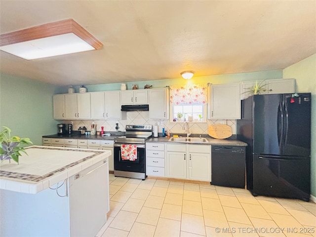 kitchen with black appliances, a sink, under cabinet range hood, decorative backsplash, and tile counters