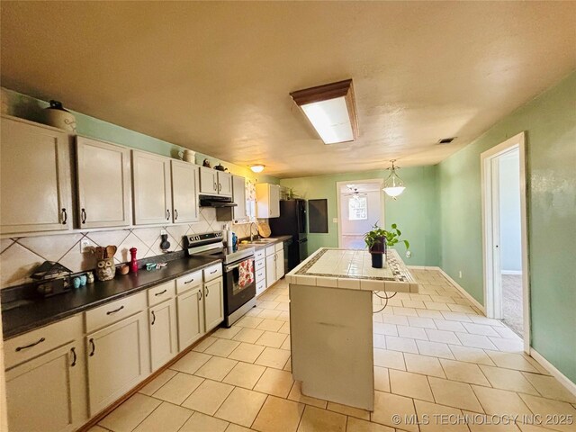 kitchen with stainless steel electric stove, freestanding refrigerator, under cabinet range hood, backsplash, and a center island