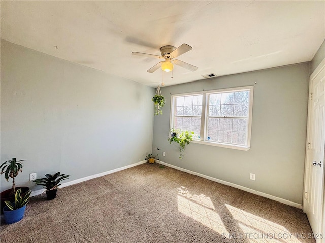 carpeted empty room with visible vents, a ceiling fan, and baseboards