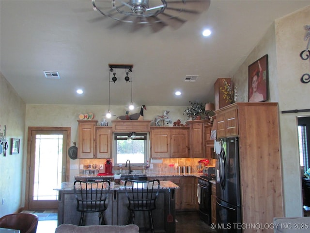 kitchen featuring black appliances, light stone counters, visible vents, and a kitchen island