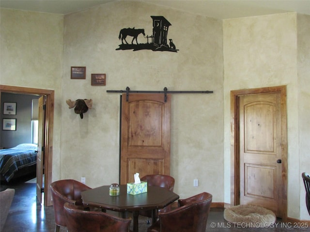 dining area featuring a barn door, a towering ceiling, and wood finished floors